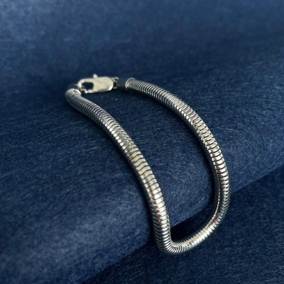 Pulseira prateada com fecho sobre tecido azul escuro