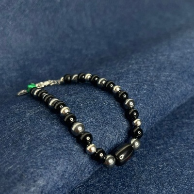 Pulseira com contas pretas e prateadas sobre tecido azul escuro