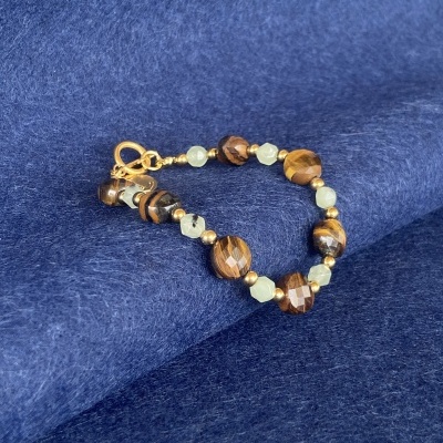 Pulseira com pedras castanhas facetadas e contas esverdeadas sobre tecido azul