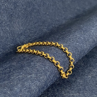 Pulseira dourada em elos redondos sobre tecido azul escuro