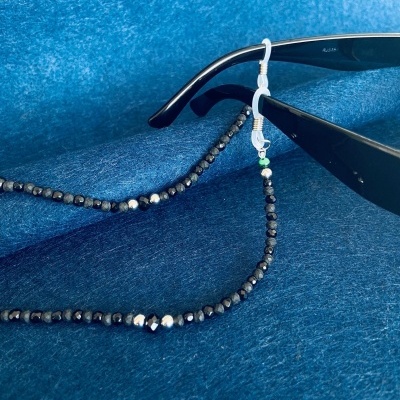 Cordão com contas para segurar óculos em tecido azul.