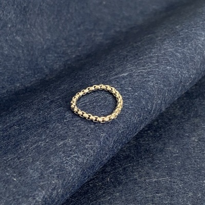 Anel dourado de elos sobre tecido azul escuro felpudo