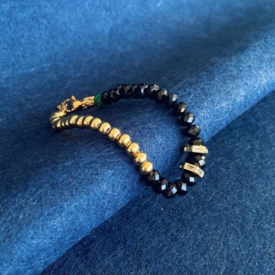 Pulseira preta e dourada sobre tecido azul