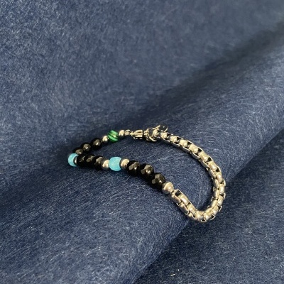 Pulseira com contas coloridas e corrente metálica sobre tecido azul escuro