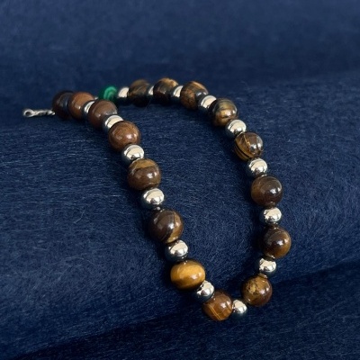 Pulseira de contas de madeira e metal prateado sobre tecido azul escuro