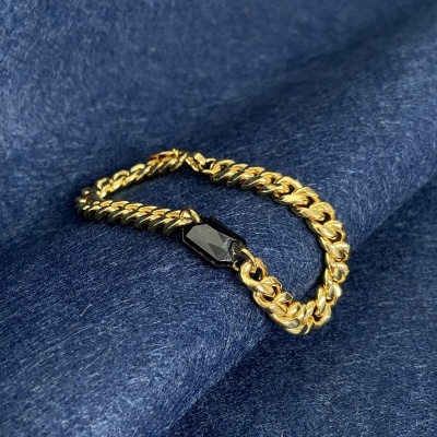 Pulseira de corrente dourada com fecho preto sobre tecido azul escuro