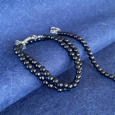 Colar e pulseira de contas pretas e cinzentas sobre tecido azul