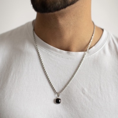 Colar prata com pedra preta usado por homem de camiseta branca