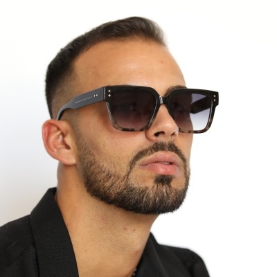 Homem a usar óculos de sol quadrados pretos com lentes escuras em fundo branco