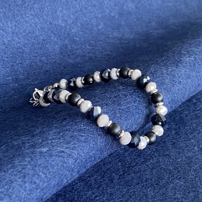 Pulseira com contas pretas, cinzentas e brancas sobre tecido azul