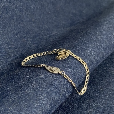 Pulseira dourada com pendentes de asas sobre tecido azul escuro