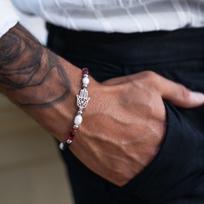 Pulseira masculina com contas coloridas e pendente de mão no pulso de homem