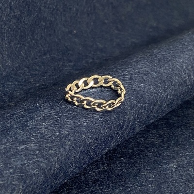 Anel de corrente dourada sobre tecido azul escuro