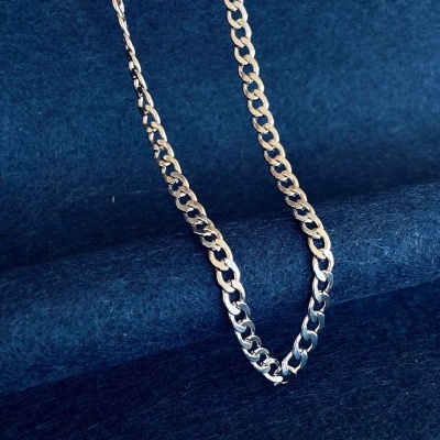 Colar em corrente de metal prateado sobre tecido azul escuro