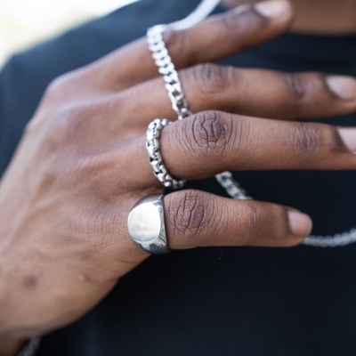 Mão masculina com anéis e corrente prateados