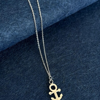 Colar prateado com pendente de âncora sobre tecido azul escuro