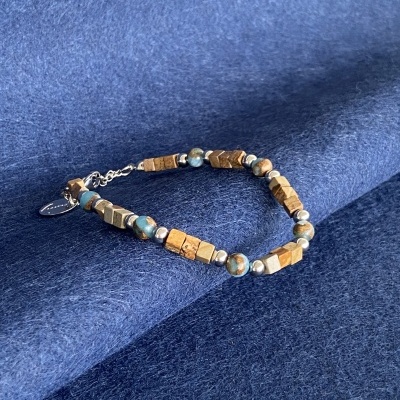 Pulseira de contas em madeira castanha, azuis marmoreadas e prateadas sobre tecido azul