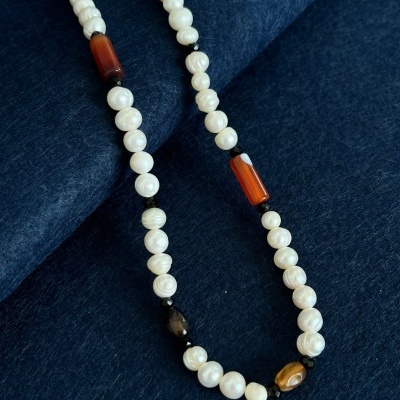 Colar de pérolas com pedras naturais sobre tecido azul escuro