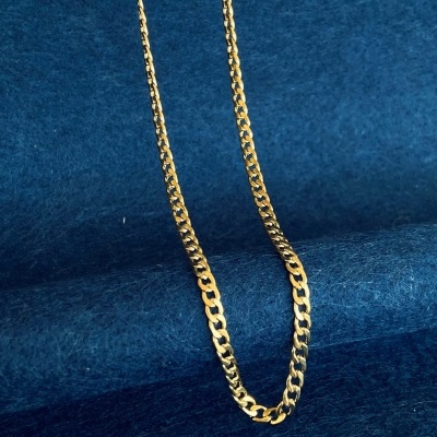 Colar corrente metal dourado sobre fundo azul