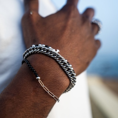 Pulseiras masculinas em vários estilos no pulso de um homem com fundo desfocado