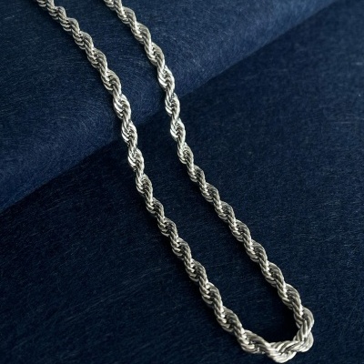 Colar de corrente de prata torcido sobre tecido azul escuro