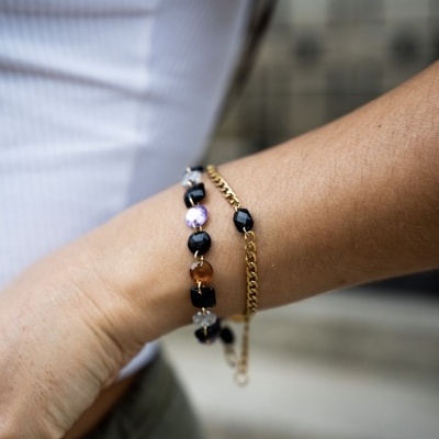 Pulseiras dourada e colorida no pulso de uma pessoa.