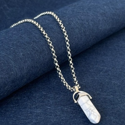 Colar com pendente de pedra branca sobre tecido azul