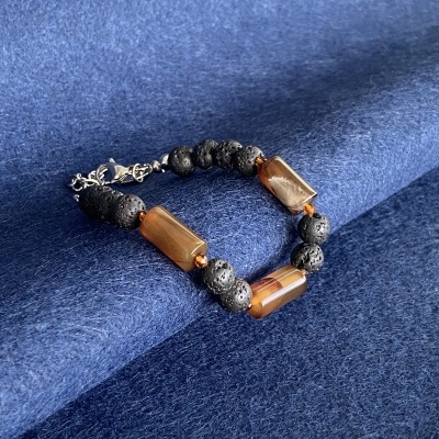 Pulseira preta e castanho-âmbar sobre tecido azul