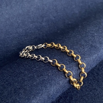 Pulseira de elos dourados e prateados sobre tecido azul escuro