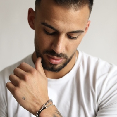 Homem com tatuagem floral e pulseira prateada em t-shirt branca