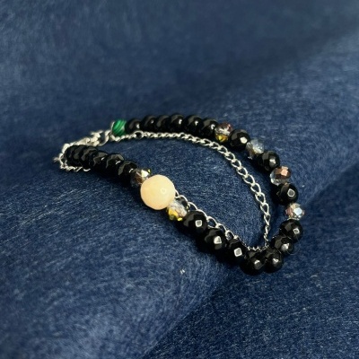 Pulseira com contas pretas e bege sobre tecido azul escuro