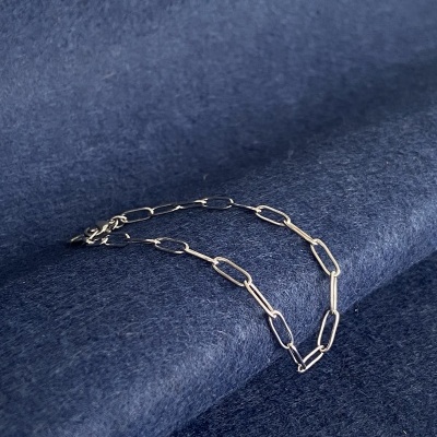 Corrente prateada com elos alongados sobre tecido azul escuro