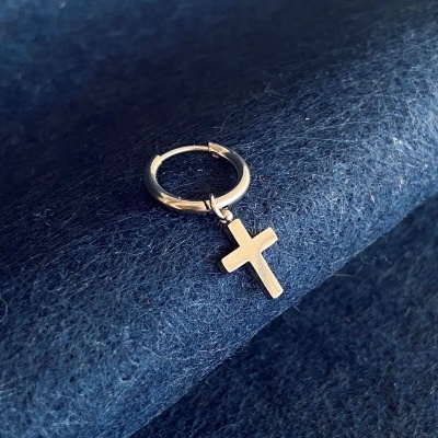 Brinco de argola com cruz em metal prateado sobre tecido azul escuro