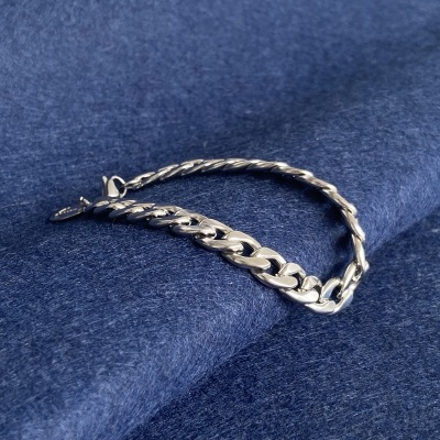Pulseira em metal prateado com elos grandes sobre tecido azul