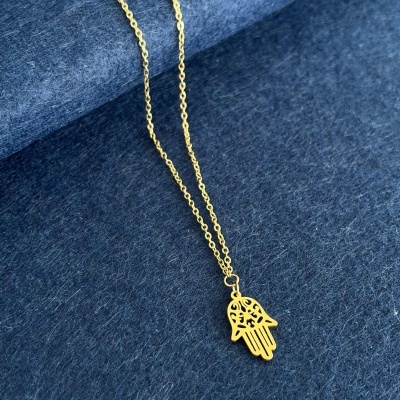 Colar dourado com pendente de mão de Fatima sobre tecido azul escuro