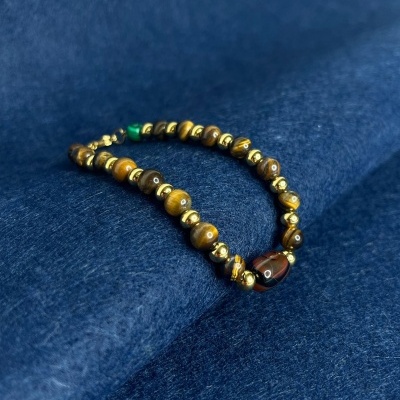 Pulseira de contas castanhas e douradas sobre tecido azul escuro