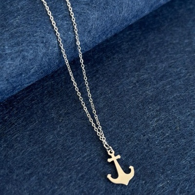 Colar prateado com pendente de âncora sobre tecido azul