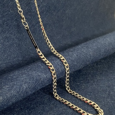 Colar de corrente metálica dourada sobre fundo azul escuro