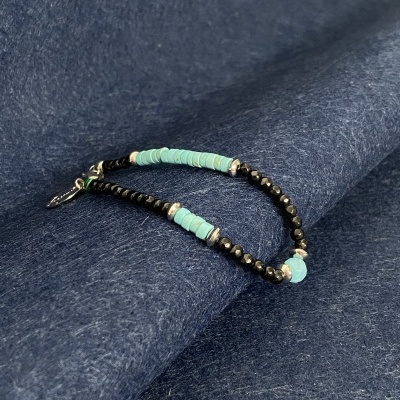 Pulseira com contas pretas e turquesa sobre tecido azul escuro