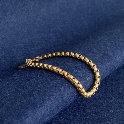 Pulseira dourada sobre tecido azul escuro