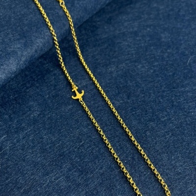 Colar dourado com pingentes de âncora sobre tecido azul