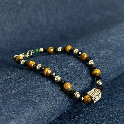 Pulseira de contas castanhas e prateadas com conta quadrada prateada em fundo azul