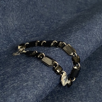 Pulseira preta e cinza metálica sobre tecido azul