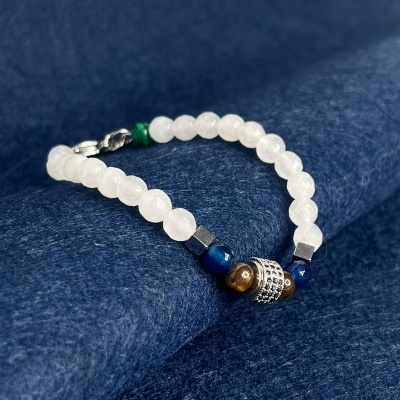 Pulseira com contas brancas, azuis, castanhas e prateada sobre tecido azul