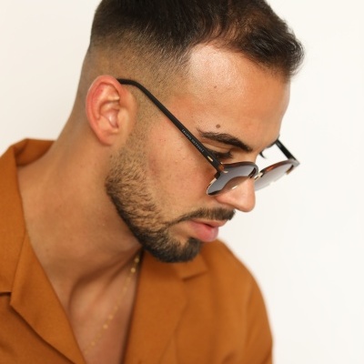 Homem a usar óculos de sol com armação preta e camisa castanha