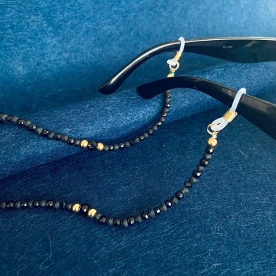 Cadeia de contas preta com detalhes dourados para óculos