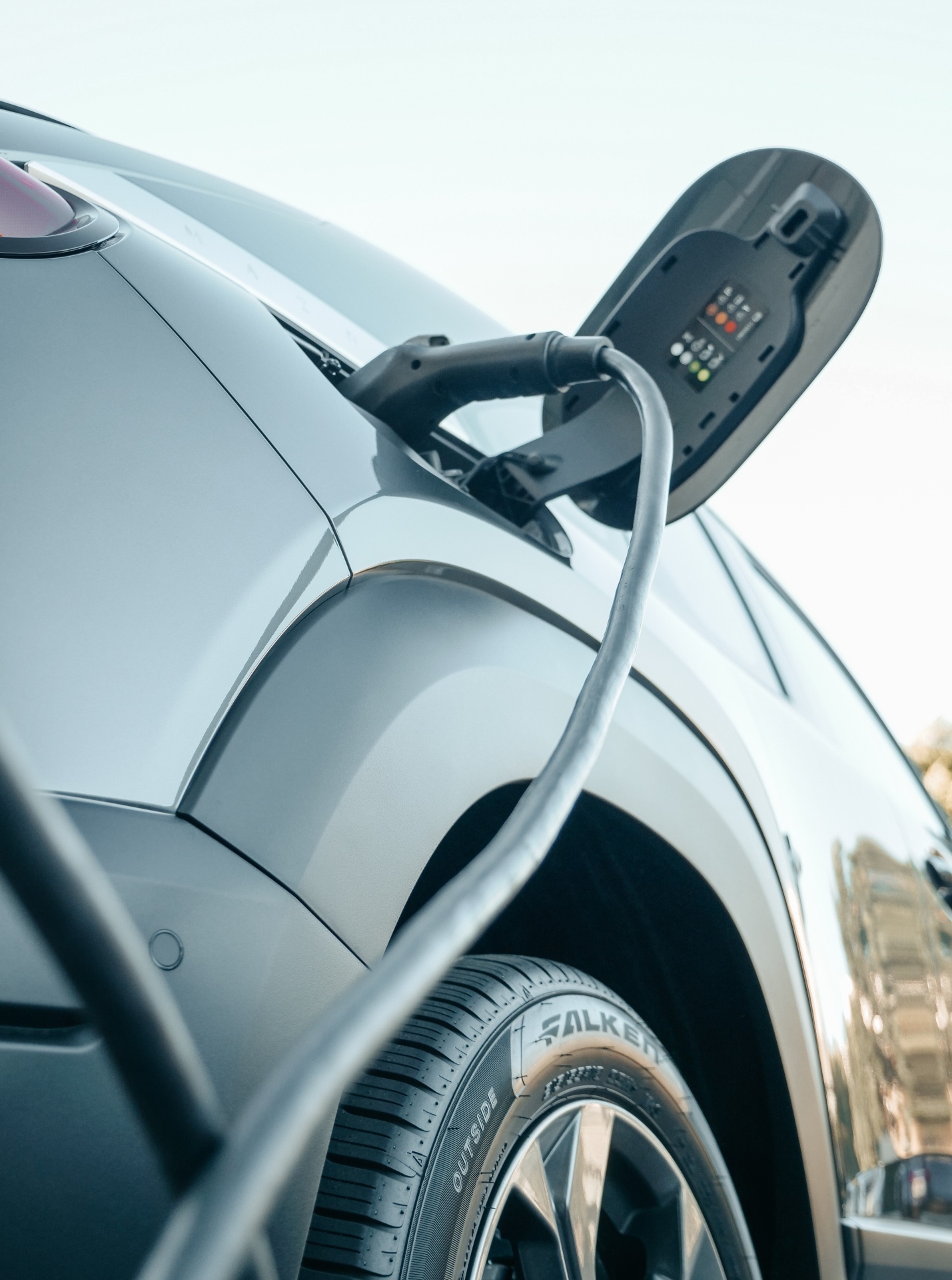 Carro elétrico cinzento a ser carregado com cabo preto