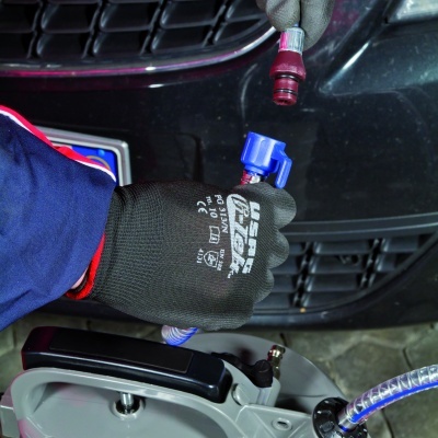 Pessoa com luvas manuseando mangueira com conetores em frente a carro preto