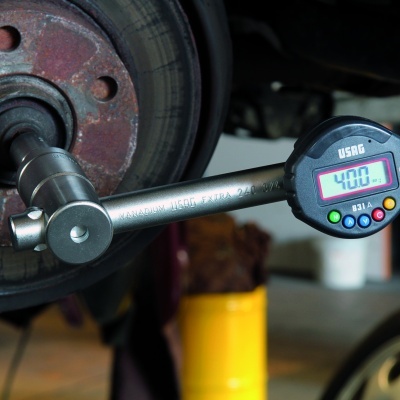 Chave dinamométrica digital USAG a medir torque junto a disco de freio enferrujado numa oficina