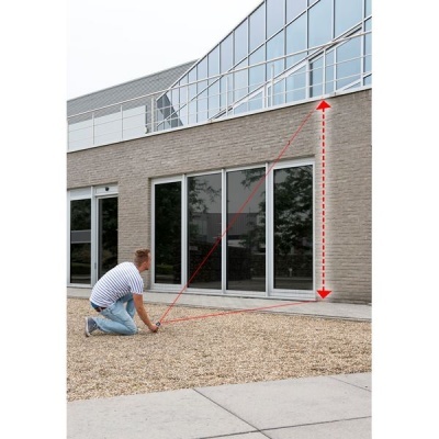 Pessoa medindo altura de varanda de vidro num prédio com parede de tijolo cinzento.
